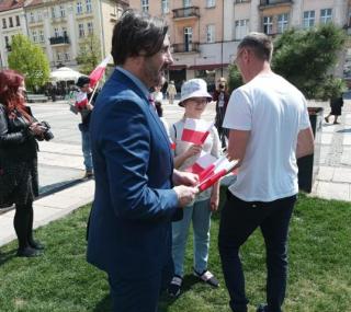 na fot.: Grzegorz Kulawinek / wiceprezydent Kalisza rozdaje flagi odwiedzającym Główny Rynek